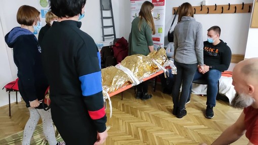 Varen prenos poškodovanih z navadnimi nosili, dogajanje spremlja predavateljica Cvetka Grm.